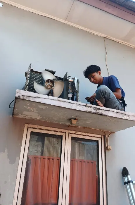 Teknisi MB Teknik Selaras servis unit outdoor AC di posisi dak